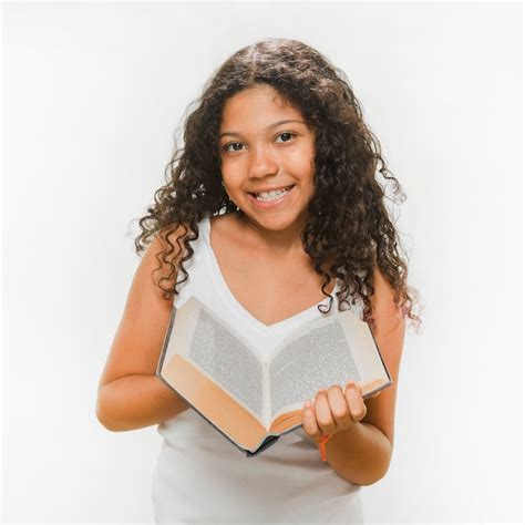 Portrait of smiling girl holding book over white background Photo ...