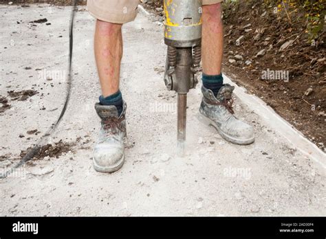 A builder using a jack hammer to break up concrete foundations Stock ...