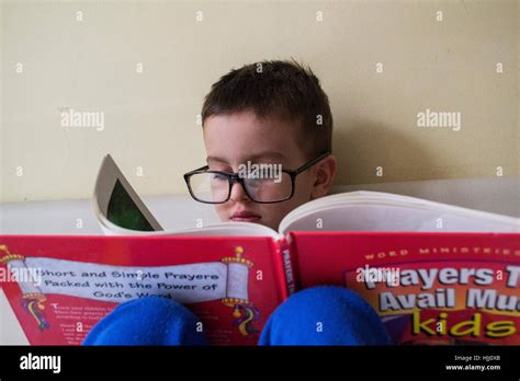 Little boy with glasses reading a book Stock Photo - Alamy