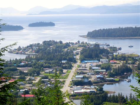 an aerial view of a small town on the water's edge with mountains in the background