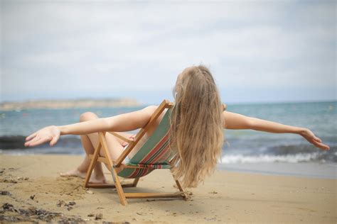 Woman in Blue and Brown Bikini Sitting on Brown Wooden Folding Chair on Beach · Free Stock Photo