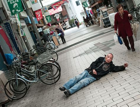 a man laying on the ground in front of parked bikes and people walking ...