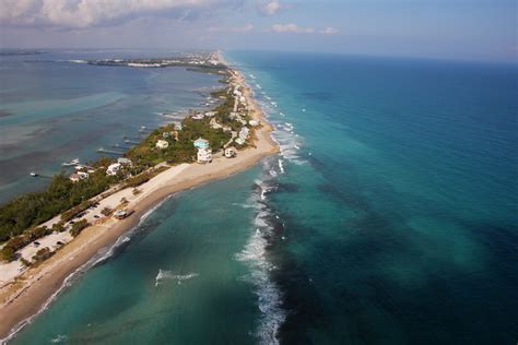 an aerial view of the beach and ocean with houses on one side ...