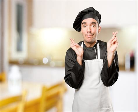 Premium Photo | Doubtful chef doing finger cross gesture