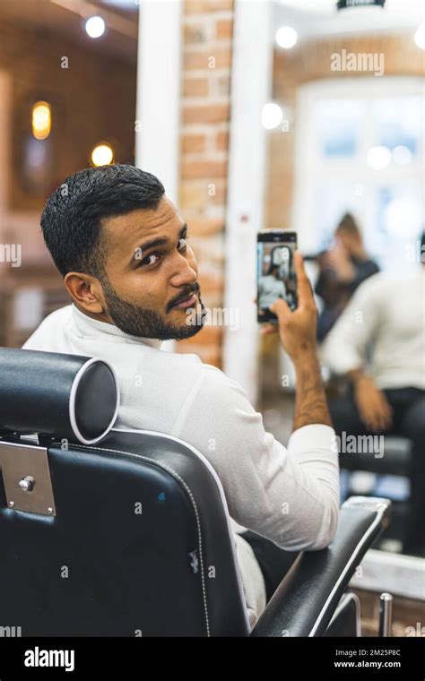 Young man taking mirror selfie after having his hair cut at barbershop. High quality photo Stock ...