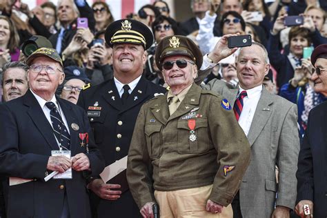 World War II veterans, service members and other attendees watch a flyover of military aircraft ...