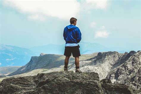 Man Wearing Blue Hoodie Standing on Top of Mountain · Free Stock Photo