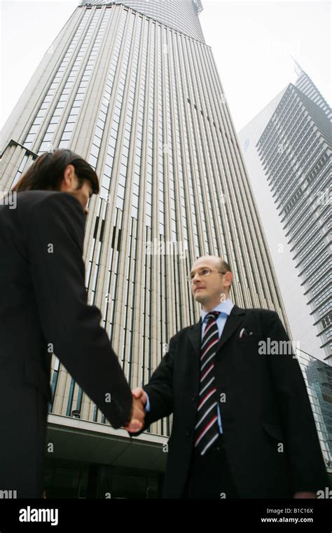 two businessmen from different cultures handshaking in the street in Shanghai,China Stock Photo ...