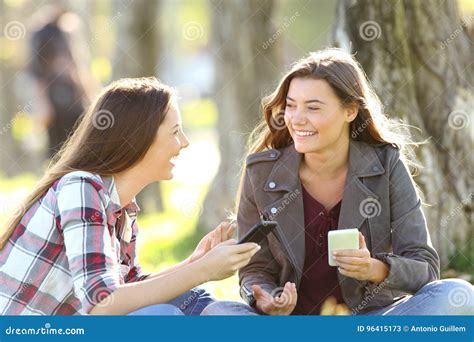 Two Friends Talking Holding Their Smart Phones Stock Image - Image of adults, city: 96415173