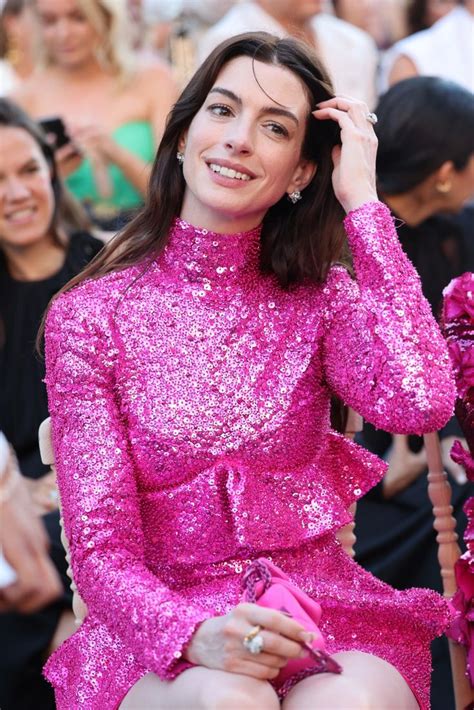 a woman in a pink sequin dress sitting on a chair with her hands behind her head