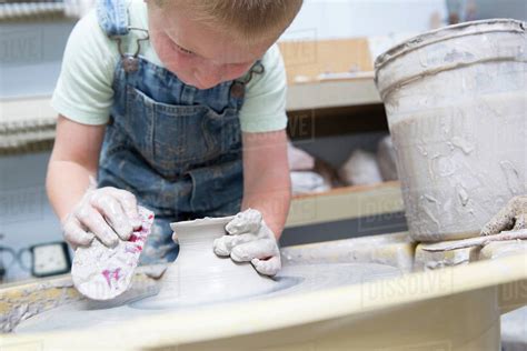 Boy shaping clay on potter's wheel - Stock Photo - Dissolve