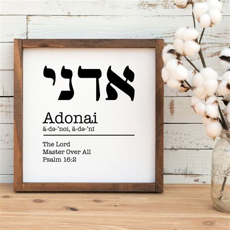 a wooden frame with the word adonai in hebrew on it next to cotton flowers