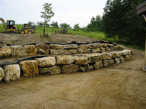 a large pile of rocks sitting on top of a dirt field next to a tractor