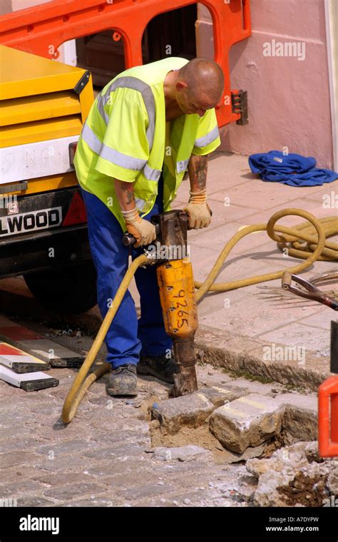 Roadworks Workman uses a pneumatic drill to dig a hole in the road England Stock Photo - Alamy