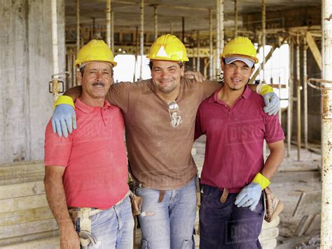 Hispanic workers hugging on construction site - Stock Photo - Dissolve