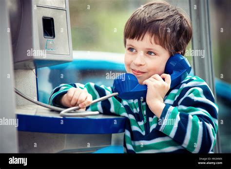 Cute little boy talking on the public phone Stock Photo - Alamy