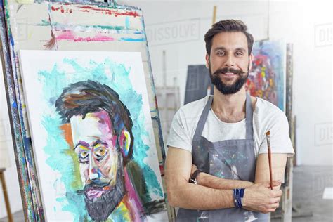 Portrait smiling, confident male artist painting in art studio - Stock Photo - Dissolve