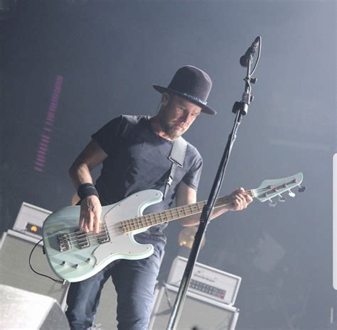 a man standing next to a microphone on top of a stage with an electric guitar