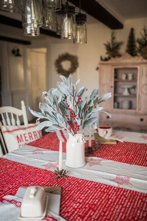 the table is set for christmas with red and white cloth on it, silver ...