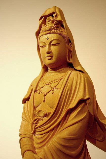 a golden buddha statue sitting on top of a wooden table next to a white wall
