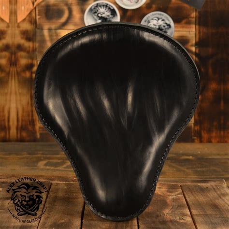 a black leather motorcycle seat on top of a wooden table next to two white plates