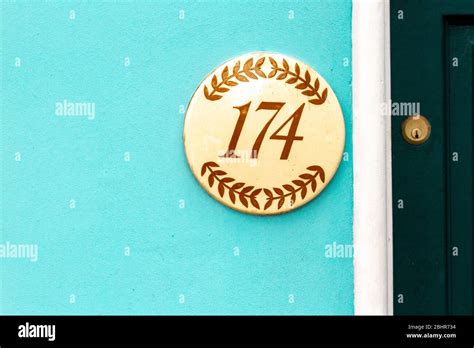 House number 174 on a round sign with laurel painted on Stock Photo - Alamy