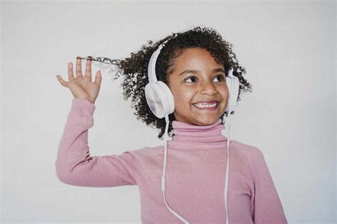 Portrait of smiling little girl listening music with headphones stock photo