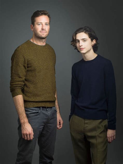 two men standing next to each other in front of a gray background ...