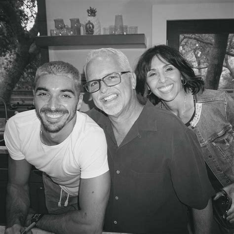 two men and a woman are posing for a photo in front of the kitchen counter