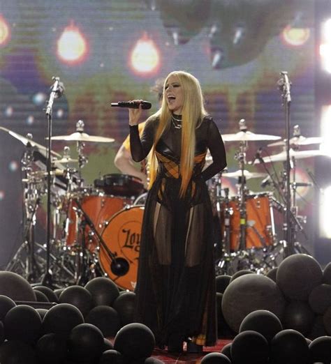 lady in black outfit singing on stage with drums and drum set behind ...