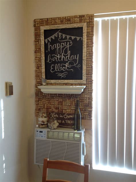 a brick wall with a chalkboard on it next to a small table and chair