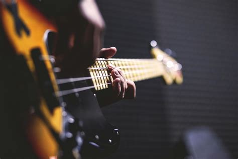 Person Playing Sun Burst Electric Bass Guitar in Bokeh Photography · Free Stock Photo