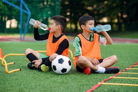 Premium Photo | Two boys in football uniforms drinking fresh water.