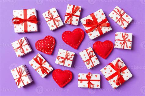 Composition of holiday white gift boxes and red textile hearts on colorful background. Valentine ...