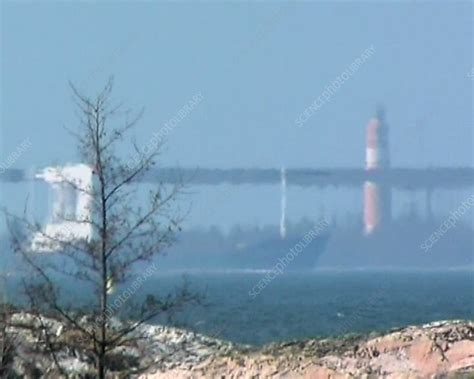 Cargo ship and lighthouse, superior mirage - Stock Video Clip - K001/3095 - Science Photo Library