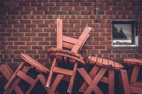 Premium Photo | Stack of wooden tables against brick wall