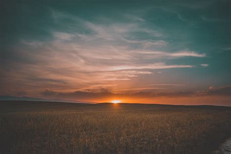 the sun is setting over an open field