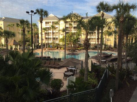 an outdoor pool surrounded by palm trees next to a building with several balconies