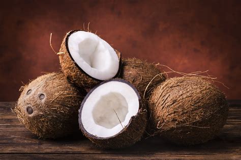 Coconut Fruits Stacked On Brown Wooden Surface · Free Stock Photo