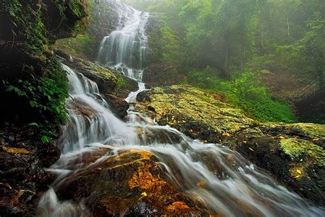 Enchanted waterfall flowing in full force through the forest admist the misty atmosphere ...