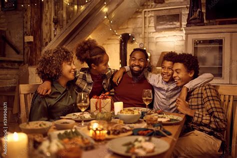 Happy multigeneration black family embracing during Thanksgiving meal at dining table. Stock ...