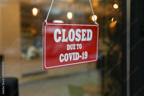 Red sign with words "Closed Due To Covid-19" hanging on glass door ...