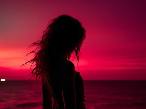 Premium AI Image | the silhouette of a woman standing on the beach at sunset