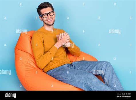 Portrait of attractive cheerful guy sitting resting in cosy chair ...