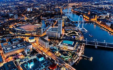 an aerial view of london at night with the river thames and city lights ...