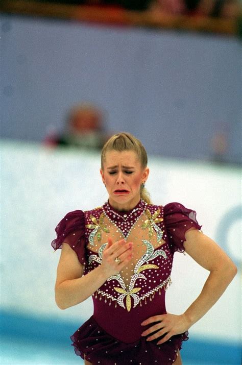 a female figure skating on the ice in a purple outfit with gold and silver accents