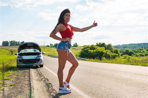 Beautiful woman hitchhiking by a broken car. girl stands at his car and waiting for help. A ...