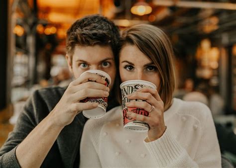 a man and woman are holding coffee mugs together in front of their faces as they look at the camera