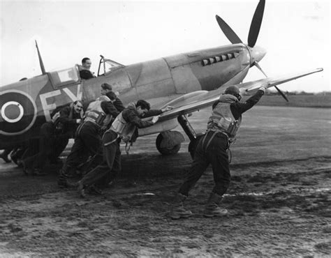 An improved Spitfire is pushed onto the runway by a group of pilots from the squadron during the ...