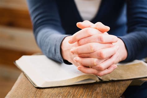 a person sitting at a table with their hands folded on top of an open book